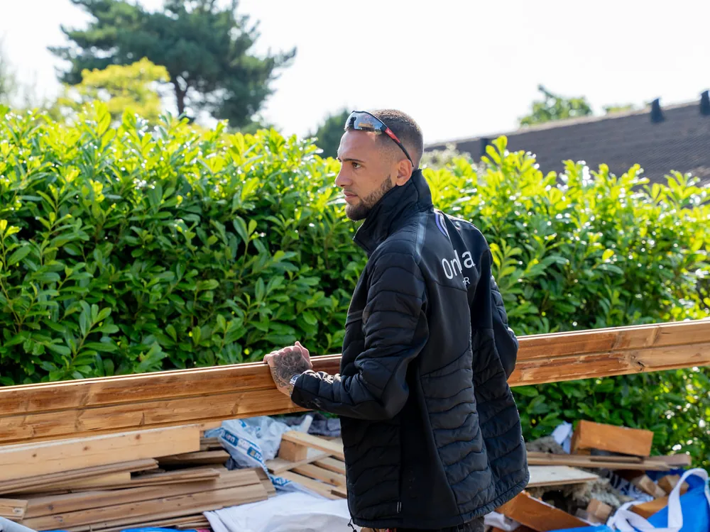 Tømrer fra OnePlan ApS bærer materialer ind på pladsen